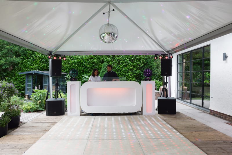 Witte DJ-booth met speakers en een discobal in een tuintent