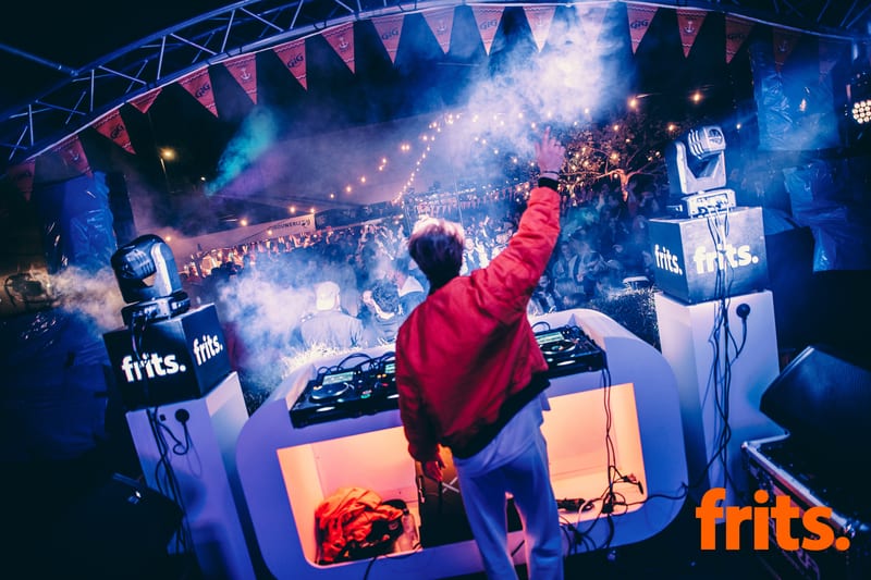 DJ op een groot podium met rook en lichtshow boven het publiek
